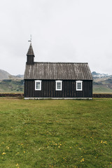 Fototapeta na wymiar Black wooden church in Iceland against the background of the mountains. Budir Church.