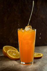 Glass of orange juice and slices of oranges on a dark background. Selective focus.
