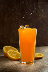 Glass of orange juice and slices of oranges on a dark background. Selective focus.