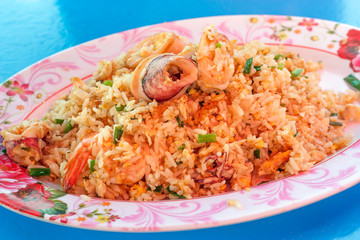 Seafood Fried rice with shrimp, squid, crab, vegetables on the dish thai style on blue table at restaurant. Thai style.