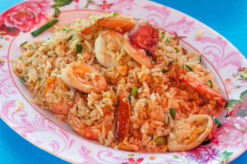 Seafood Fried rice with shrimp, squid, crab, vegetables on the dish thai style on blue table at restaurant. Thai style.