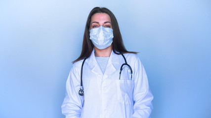 Portrait girl (woman) in a medical uniform. A mask on her face is standing in a ward (hospital), crossing her arms and smiling. Concept of: Nurse, Medical Assistant, Communication, Selfie, Smartphone.