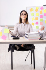 Young female employee doing exercises at workplace 