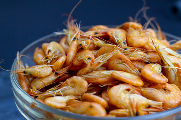A full bowl of bright, tasty, boiled shrimp - wholesome seafood. Selective focus with blurred background.