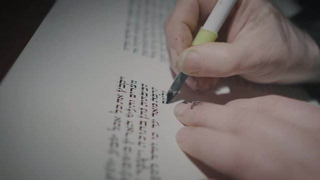 Cinematic shot of the man writing a Torah scroll