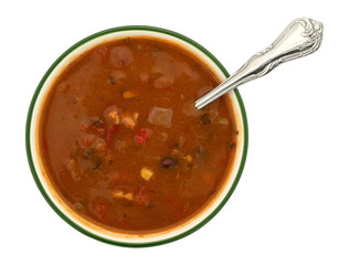 Top view of a bowl of chicken tortilla soup with a spoon in the food isolated on a white background.