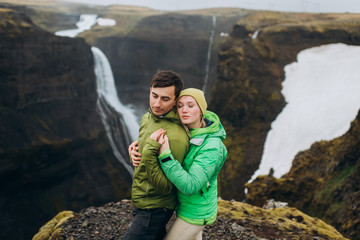 Naklejka premium Сouple hugging near the canyon. Tourists in the nature in green jackets.