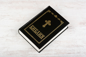 Holy Bible on white wooden background. Religion concept and faith. Cyrillic text means Bible in bulgarian and russian