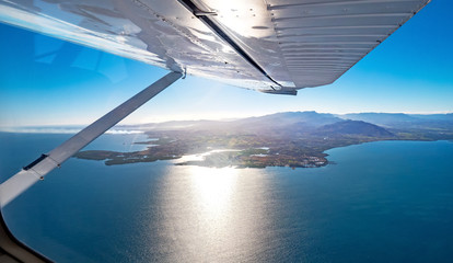View from under a seaplane wing flying over a paradise island