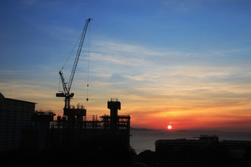 Building silhouettes and Industrial construction cranes on beautiful sunset background