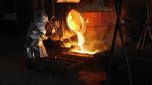 Man working with liquid metal in factory. Metal factory