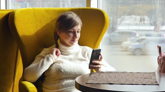 Beautiful woman taking a selfie on her smartphone while sitting in a cafe. Business lunch. Slow motion