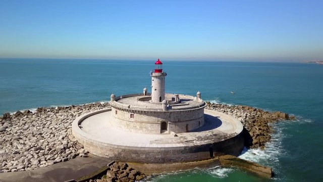 Aerial, drone shot, orbiting around Bugio lighthouse, on a rocky island, at the atlantic ocean, on a sunny day, near the Oeiras coast and Tejo river, in Lisbon, Portugal