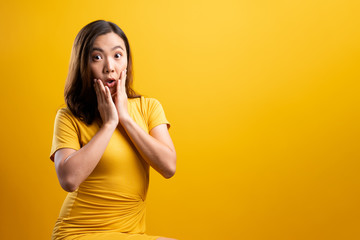 Portrait of excited woman isolated over yellow background