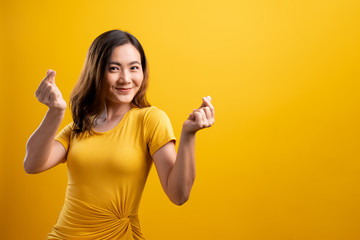 Woman in love showing heart isolated over yellow background - obrazy, fototapety, plakaty