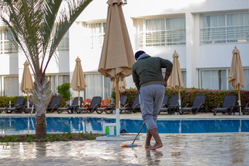Floor washers in the Egyptian hotel in the morning are washing the marble floor by the pool with brushes. Pool washers and hotel cleaners work. January 28, 2019, Sharm El Sheikh, Egypt.