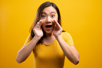 Woman make gossip gesture isolated over yellow background