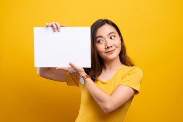 Obraz na płótnie Canvas Woman showing paper copy space isolated over yellow background