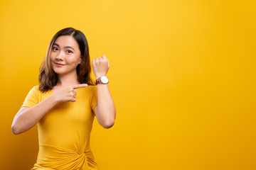 Happy woman holding hand with wrist watch isolated on a yellow background - Powered by Adobe