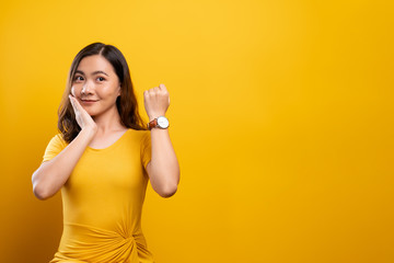Happy woman holding hand with wrist watch isolated on a yellow background