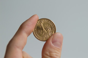 United States one dollar coin with Liberty Statue being held by fingers