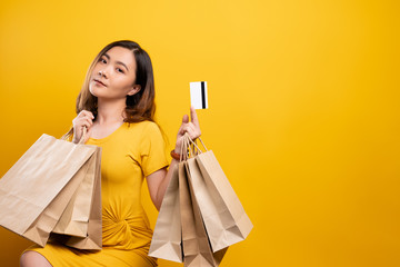 Portrait of woman holding shopping bags and credit card isolated over background