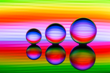 A row of three crystal balls with multicolored light painting behind them