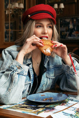 beautiful woman with blond hair in casual clothes and red hat sitting in cafe