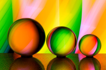 A row of three crystal balls with multicolored light painting behind them