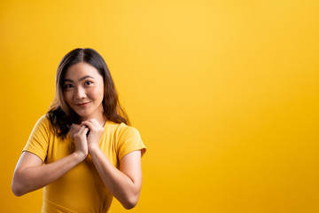 Woman showing her heartfelt gratitude on isolated yellow background