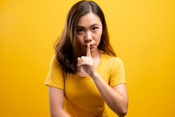 Woman show a quiet sign isolated over yellow background