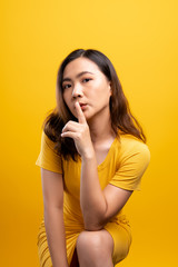 Fototapeta premium Woman show a quiet sign isolated over yellow background