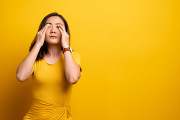 Woman has eyes pain isolated over yellow background