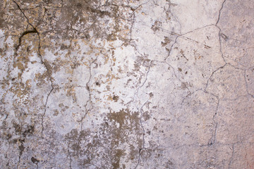 old, battered, damaged white concrete wall with cracks and dark paint and mildew stains. rough surface texture