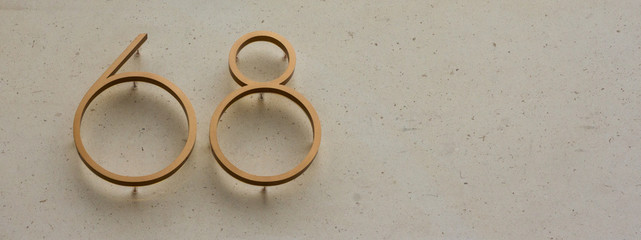 Elegant gold house number sixty-eight with the 68 attached to a white marble background