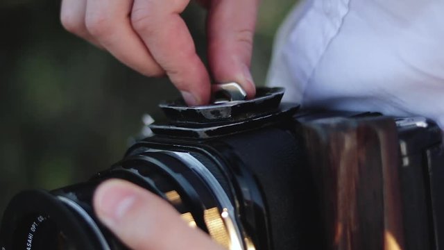 Photographer attaches a tripod pad to the medium format camera.