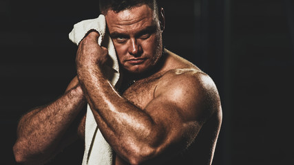 Strong athletic handsome man wiping body after training, with color imitating social network filter