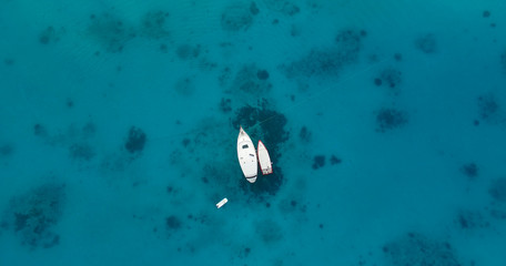 Aerial top view of two boats or yachts moored in the middle of the ocean, sea or a a lagoon. Yacht week, crystal clear water. Concept: luxury yachts on turquoise water, travel agency