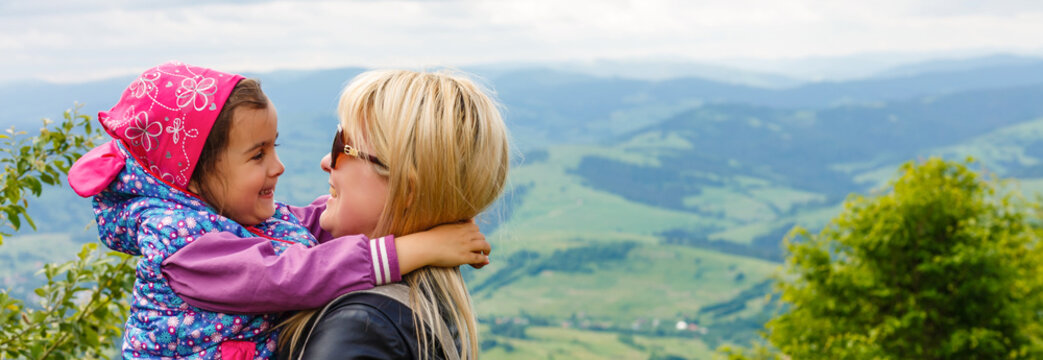 mother and daughter stand on a mountain and gaze off into the distance