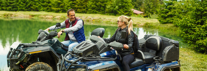 Young couple having fun on mountain while driving a quad bike on a summer day. Young man and woman on an ATV. © Angelov