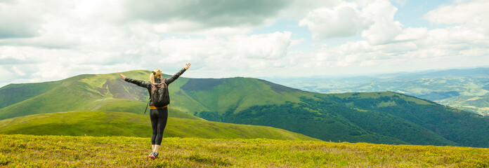 Young woman standing on cliff's edge and looking into a wide valley
