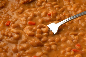 Hot baked beans with bacon in a tomato sauce with a fork in the food