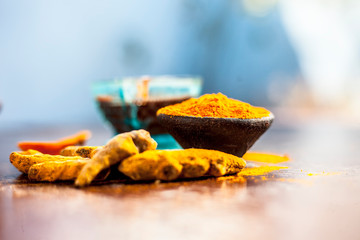 Tamarind or imli or amli in a clay bowl along with its roasted seeds on wooden surface with turmeric or haldi in a clay bowl used for treating acne and pimple.
