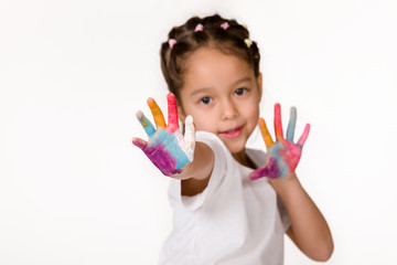 cute little child girl with hands painted in colorful paint shows stop gesture isolated on white background.
