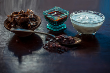 Ingredients of tamarind face pack on wooden surface which are Raw tamarind,raw curd or yogurt and rock salt.Made face pack in blue colored glass bowl.Used to clean bacteria from skin.