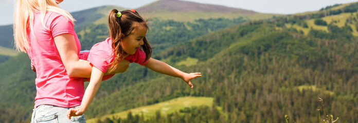 Mother and daughter playing circling around in the mountains on beautiful. Mother turns little...