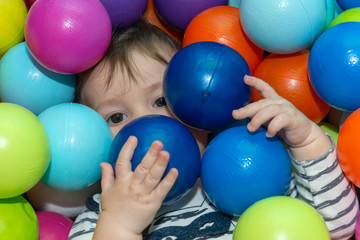 Fototapeta na wymiar The baby boy is playing with color balls