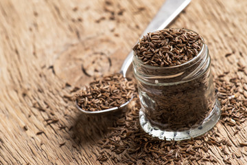 Caraway grain in the jar, vintage wooden background, selective focus