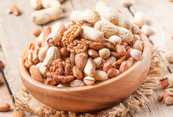 Nuts set assortment in bowl with almonds, pistachios, cashews, hazelnuts, peanuts, Brazil nuts, walnuts, vintage wooden kitchen table background