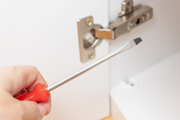 Adjustment of furniture doors using a screwdriver, assembling furniture concept